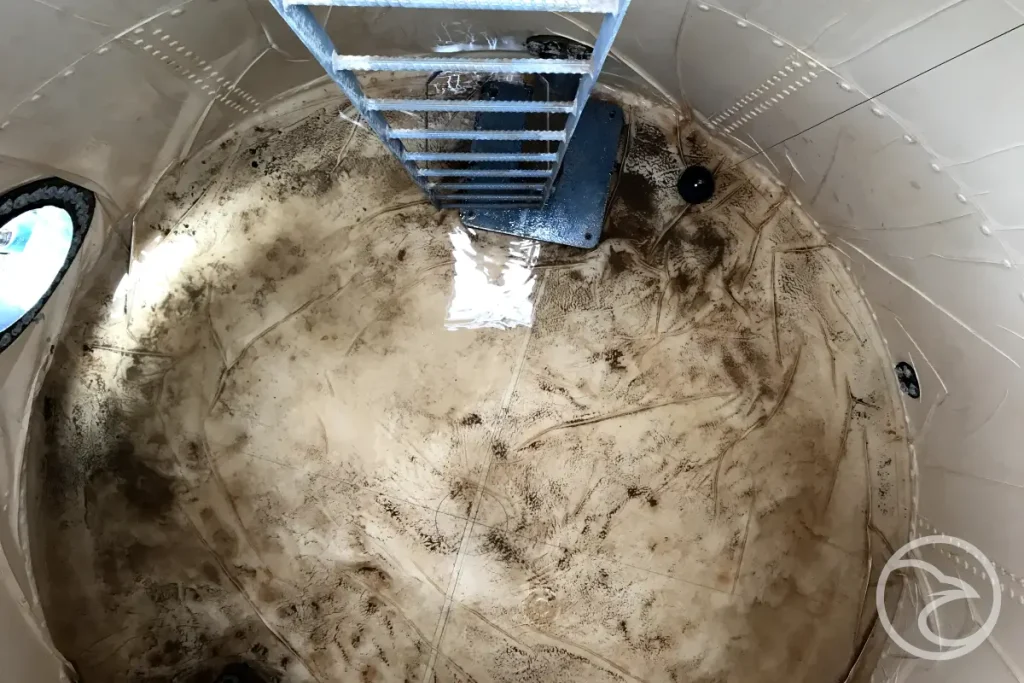 Worker cleaning sediment from inside a fire water tank